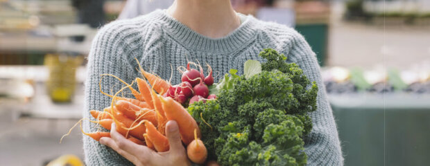 Der Fotoausschnitt zeigt eine Frau auf einem Markt beim Einkauf regionaler Gemüse-Produkte.